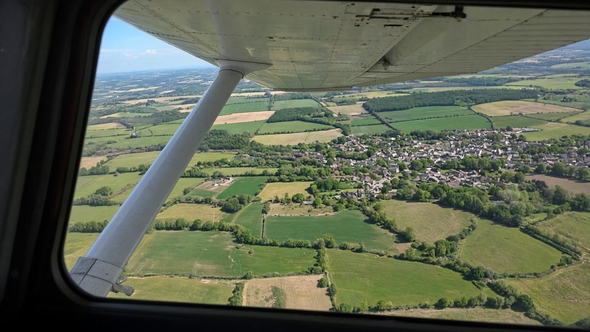 View from the cockpit of a high-wing aircraft looking down over English countryside
